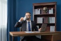 Successful vintage happy business blonde, white man, Caucasian person working in office and drinking a cup of coffee with computer