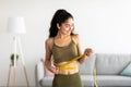 Successful weight loss concept. Fit young Indian woman in sports clothes measuring waist with tape at home Royalty Free Stock Photo