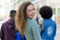 Successful white female student with backpack and friends showing thumb up