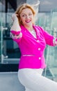 Successful woman entrepreneur in a magenta jacket posing on the terrace of a cafe in a business center. Royalty Free Stock Photo