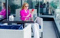 A successful woman entrepreneur in a magenta jacket serf the Internet on the terrace of a cafe in a business center. Royalty Free Stock Photo