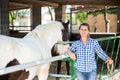 Successful woman farmer near enclosure with horses