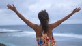 Successful young woman reached top of moutain. Girl rise her hands in the air. Top view on beautiful ocean between rocks