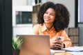 Successful young African American pretty woman, entrepreneur in casual wear, smiling, working on laptop in a modern Royalty Free Stock Photo