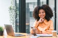 Successful young African American pretty woman, entrepreneur in casual wear, smiling, working on laptop in a modern Royalty Free Stock Photo