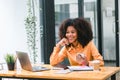 Successful young African American pretty woman, entrepreneur in casual wear, smiling, working on laptop in a modern Royalty Free Stock Photo