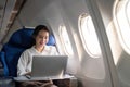 Successful young asian business woman sits in airplane cabin plane and working from anywhere. Flying at first class Royalty Free Stock Photo