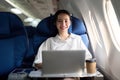 Successful young asian business woman sits in airplane cabin plane and working from anywhere. Flying at first class Royalty Free Stock Photo