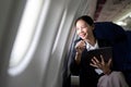 Successful young asian business woman sits in airplane cabin plane and working from anywhere. Flying at first class Royalty Free Stock Photo