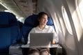 Successful young asian business woman sits in airplane cabin plane and working from anywhere. Flying at first class Royalty Free Stock Photo