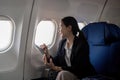 Successful young asian business woman sits in airplane cabin plane and working from anywhere. Flying at first class Royalty Free Stock Photo