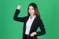 Successful young Asian business woman in suit raising hands and smiling on green isolated background