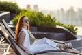 Successful young asian businesswoman sitting on the swimming pool bed looking at the view during sunset for classy summer resort Royalty Free Stock Photo