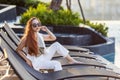 Successful young asian businesswoman sitting on the swimming pool bed looking at the view at sunset for classy summer resort Royalty Free Stock Photo