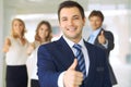 Successful young business people showing thumbs up sign while standing in office interier Royalty Free Stock Photo