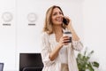 Business woman drinking coffee and having phone conversation while working at the office Royalty Free Stock Photo