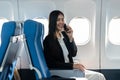 Successful young business woman working speaking on mobile phone while while sitting on aircraft cabinin Royalty Free Stock Photo