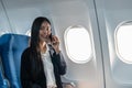 Successful young business woman working speaking on mobile phone while while sitting on aircraft cabinin Royalty Free Stock Photo