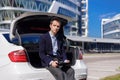 Successful young businessman freelancer working outside in the city. man sit on car boot with tablet Royalty Free Stock Photo