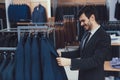 Successful young businessman looks at jacket in business mens clothing store. Royalty Free Stock Photo