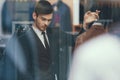 Successful young businessman looks at jacket in business mens clothing store. Royalty Free Stock Photo