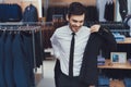 Successful young businessman measures jacket in business mens clothing store. Royalty Free Stock Photo