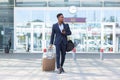 Successful young confident African American businessman moving with cellphone in hands against modern office building background Royalty Free Stock Photo