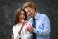 Successful young couple with piggy bank on grey background