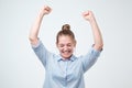 European strong successful young female winner in blue shirt raising arms exclaiming with joy and excitement. Royalty Free Stock Photo