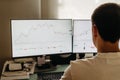 Successful young trader in casual wear working with charts and market reports at home