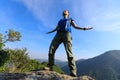 Woman backpacker breathing fresh air at cliff edge on top of mountain Royalty Free Stock Photo