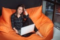 Successful young woman sitting on sofa in office, working on her laptop. Royalty Free Stock Photo