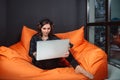 Successful young woman sitting on sofa in office, working on her laptop. Royalty Free Stock Photo