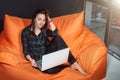 Successful young woman sitting on sofa in office, working on her laptop. Royalty Free Stock Photo