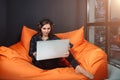 Successful young woman sitting on sofa in office, working on her laptop. Royalty Free Stock Photo