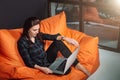 Successful young woman sitting on sofa in office, working on her laptop. Royalty Free Stock Photo