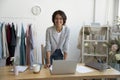 Successful young woman workshop owner posing at desk enjoying work