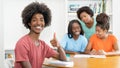 Successfull black male student at desk with group of learning african american students Royalty Free Stock Photo