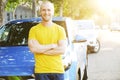 Successfull happy young man and his car in soft sunset light on urbanistic background. Busines man with vehicle on roadside. Royalty Free Stock Photo