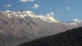 Successive Snowy Mountain Ridge at Edge of Forest in Spring