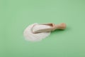 Succinic acid powder in wooden scoop on green background