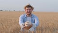 Sucessful young farmer, happy rural guy gives you tasty rooty and smiles staying in grain wheat bread field at autumn