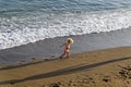 A small child runs along the edge of the surf