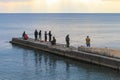 Fishermen on a concrete pier catch fish on a fishing rod in the Black Sea at sunset dly Royalty Free Stock Photo