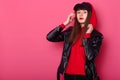 Sudio portrait of young beautiful fashionable teenager girl wearing leather jacket, red hoody and black cap, posing isolated over Royalty Free Stock Photo