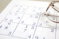 Sudoku and eyeglasses on table, closeup view Royalty Free Stock Photo