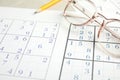 Sudoku and eyeglasses on table, closeup view Royalty Free Stock Photo