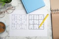 Sudoku, pen, planner, glasses and cup of coffee on white marble table, flat lay Royalty Free Stock Photo