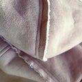 Suede outerwear with a hood. Beige faux suede with sheepskin on the fold of a demi-season garment. seams in the material