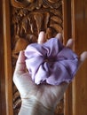 Suede scrunchie in purple colour with balinese carved wood as background